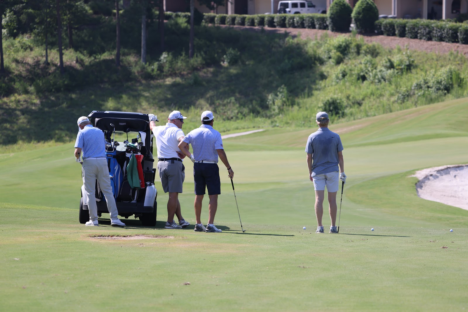 A tournament foursome gathered with their cart on the course