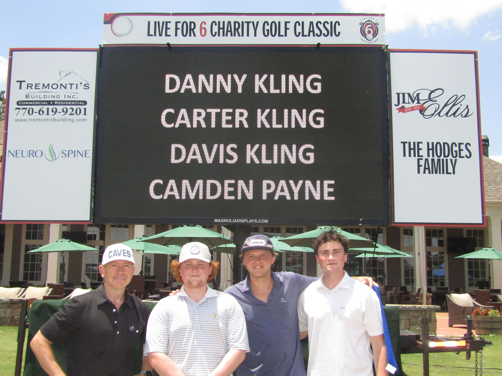 A Live for 6 team gathered beneath the Charity Golf Classic scoreboard